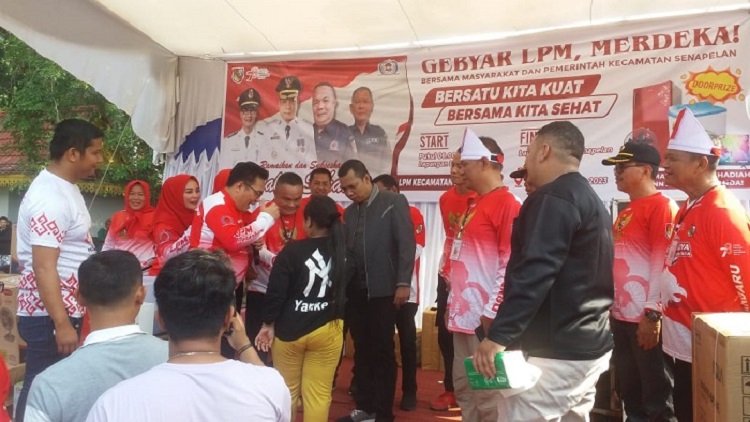 Penjabat Wali Kota Pekanbaru Muflihun dan Sekjen LPM RI Idham Dalimunthe memberikan kuis dan hadiah doorprize kepada warga yang ikut Gerak Jalan Sehat guna memeriahkan HUT LPM RI ke-23 dan Rakernas di Kota Pekanbaru. Foto: LPM Pekanbaru